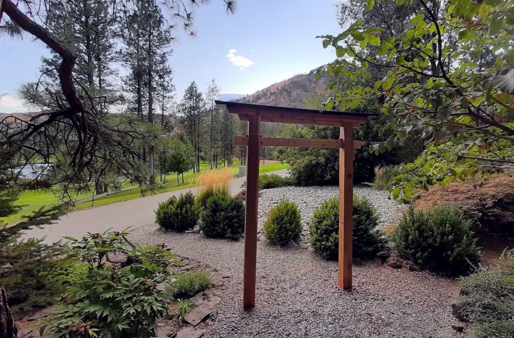 St. Andrews by the Lake BC Canada, photograph of a wooden torii gate surrounded by greenery, evoking themes of passage and nature’s quiet order – constructed by George Wendell Baker